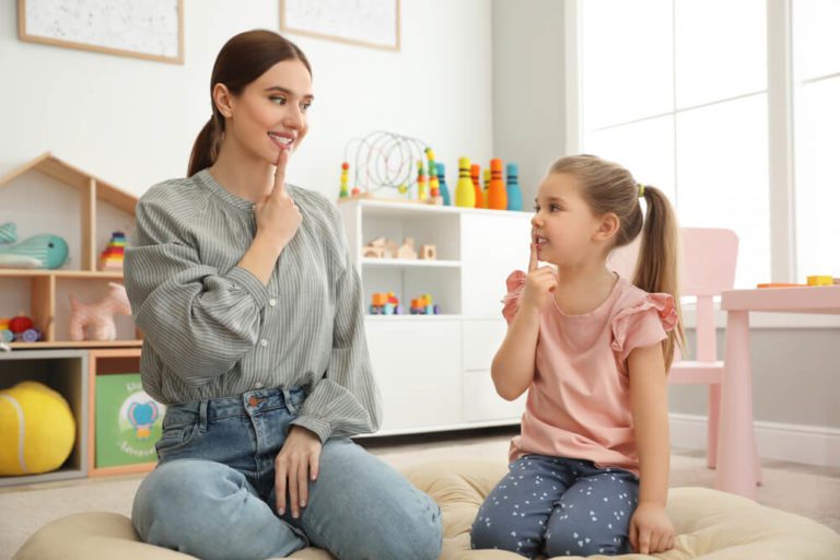 Speech therapist working with little girl in office